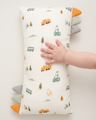 A baby's hand resting on a Little Rei train-print pillow