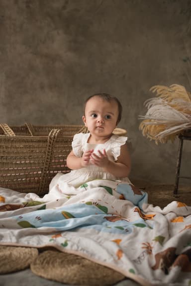 A baby sitting up among spread-out bamboo muslins