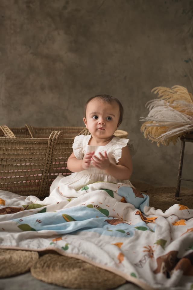 A baby sitting up among spread-out bamboo muslins