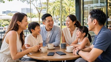 Three generations of a family laughing together around an outdoor cafe table with coffee cups, palm trees and city buildings behind