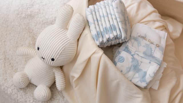 Folded Little Rei diapers beside a soft toy, ready to pack