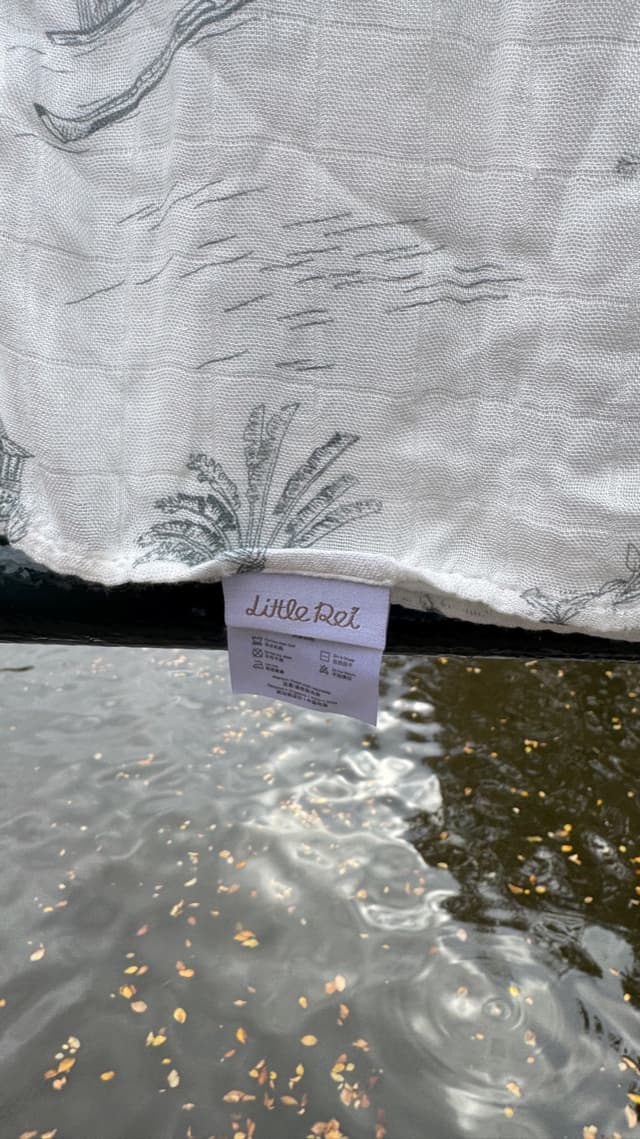 A single bamboo muslin swaddle hanging unfolded, its Little Rei label showing