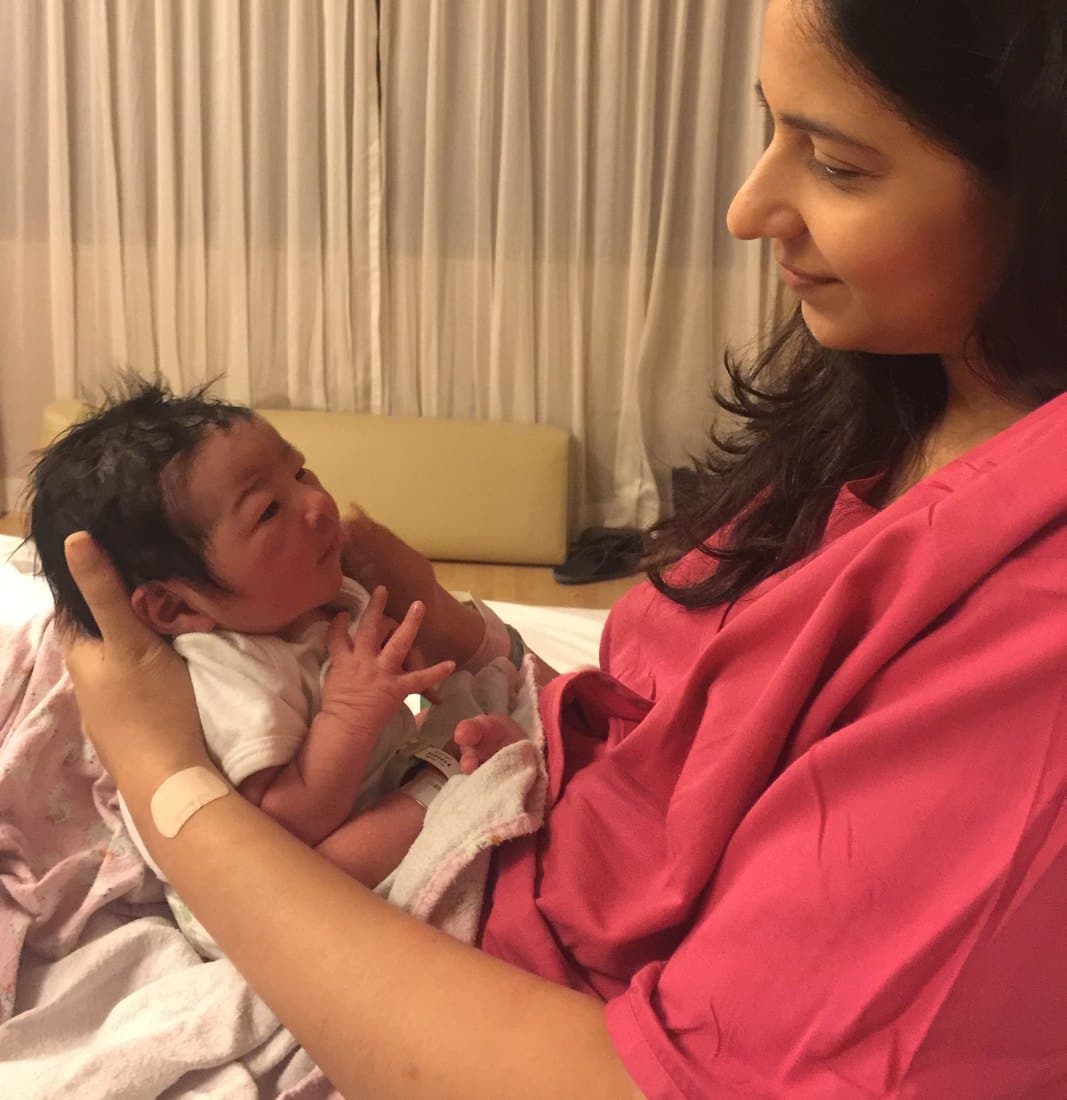 Roshni Mahtani Cheung holding her newborn daughter Shan, looking down at her