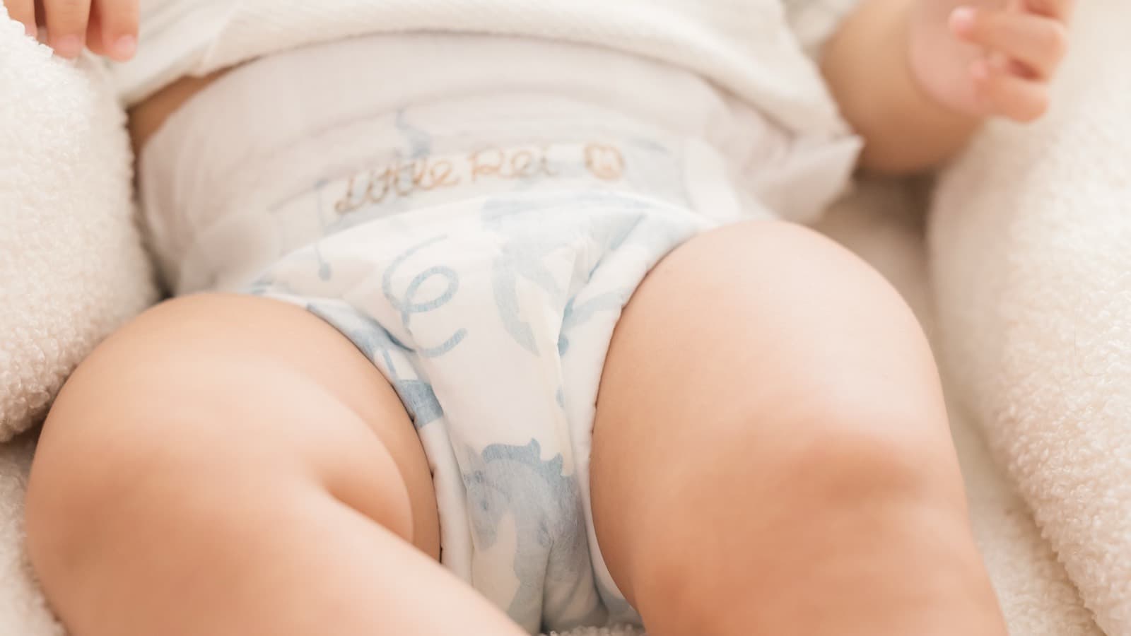 A baby lying on a bed at rest in a Little Rei tape diaper