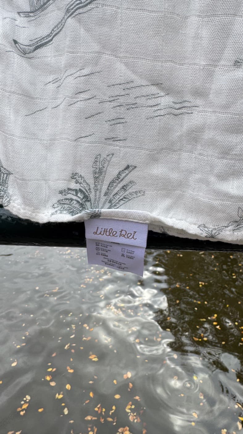 A single bamboo muslin swaddle hanging unfolded, its Little Rei label showing