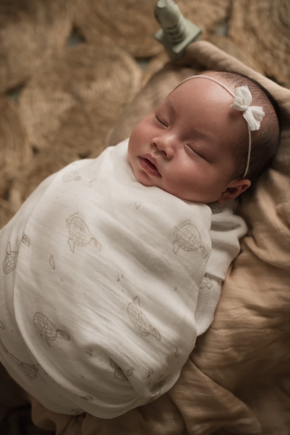 A newborn fast asleep, wrapped closely in a soft bamboo muslin