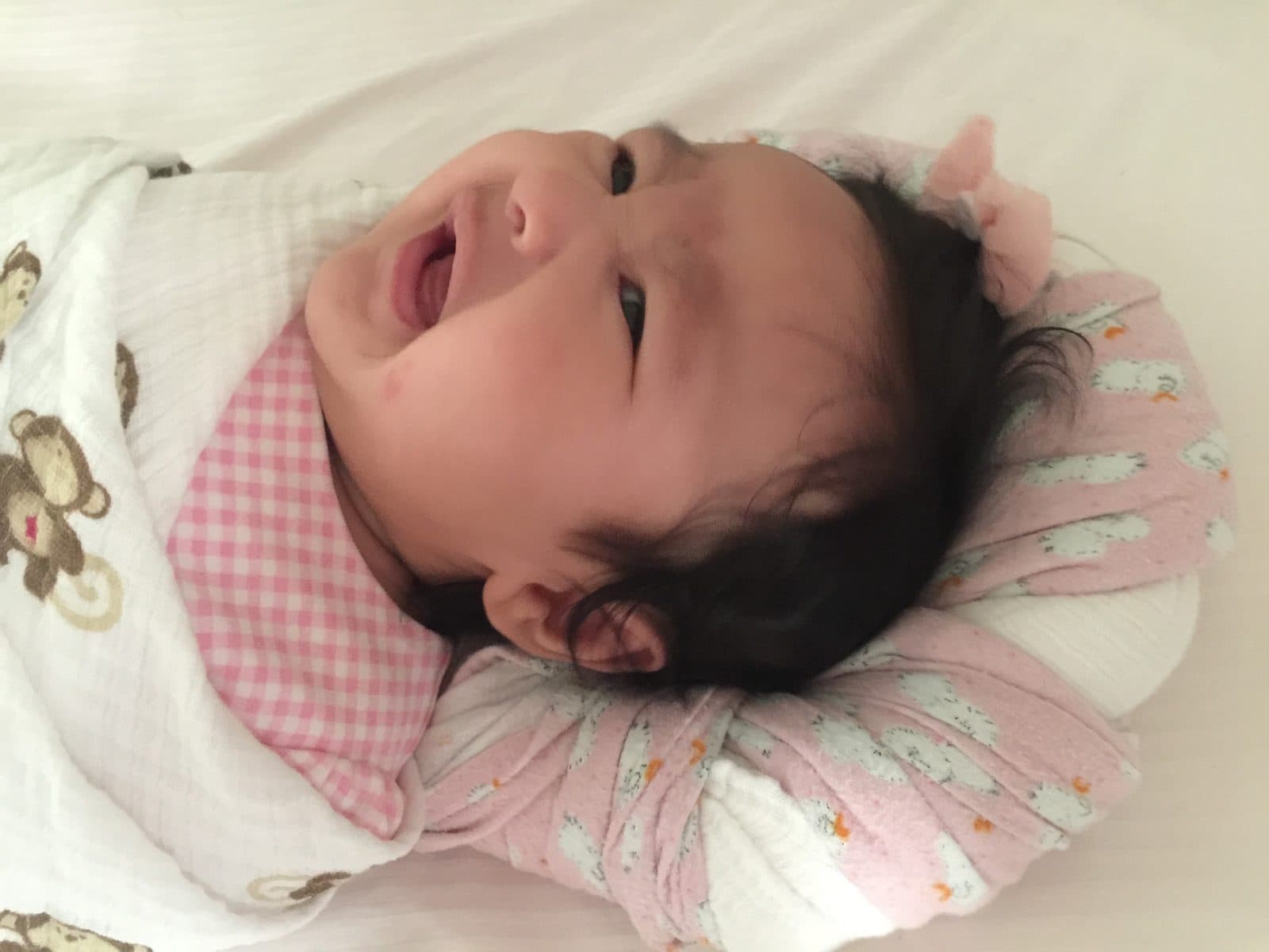 Shan swaddled in a monkey-print muslin, head turned and mouth open mid-cry