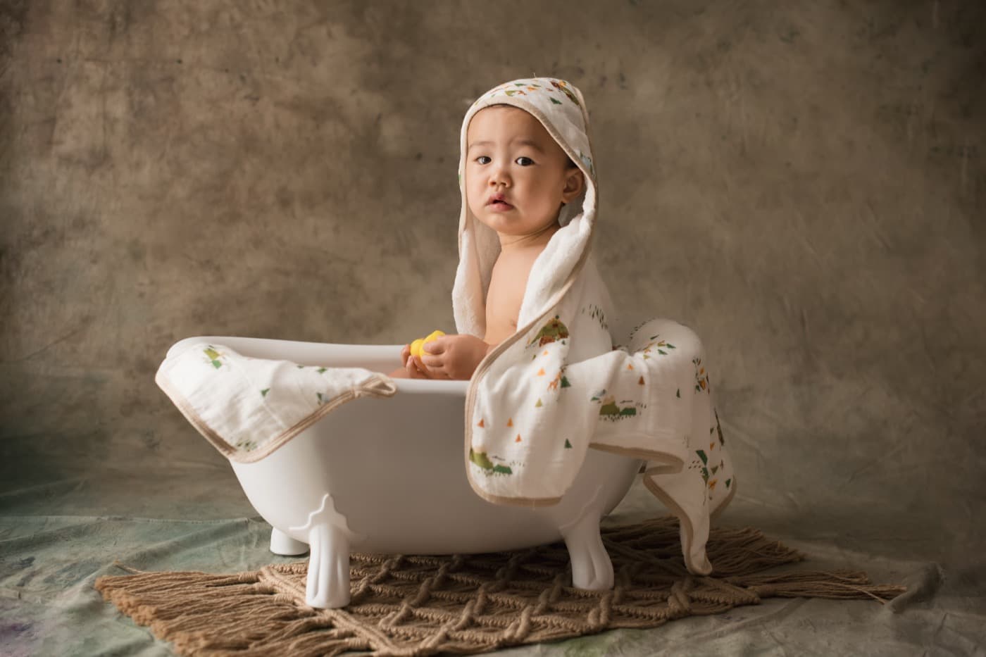 A small child sitting in a roll-top bath with a towel wrapped around their hair