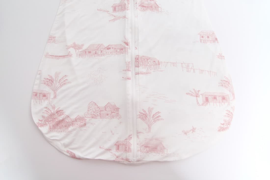 A Little Rei sleep sack in a pink village print, laid flat
