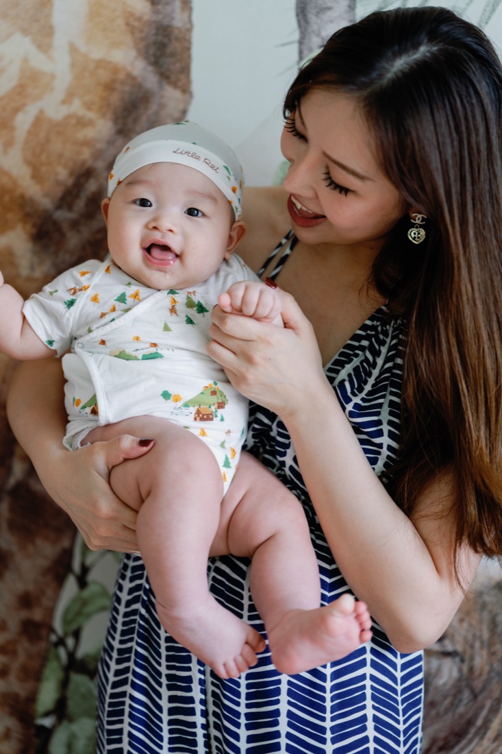 Mum holding baby wearing a Little Rei rainforest cap