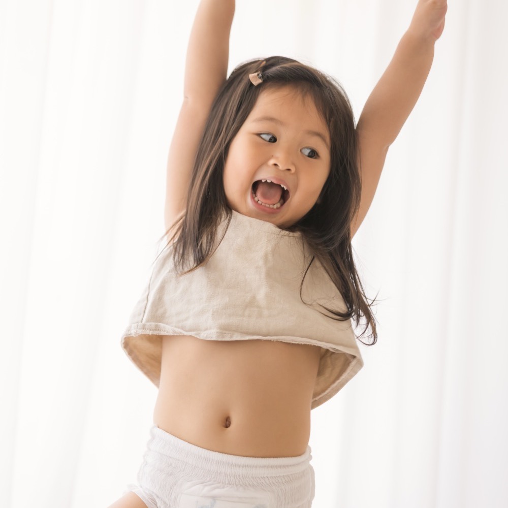 A toddler throwing their arms up with joy in Little Rei bamboo pull-up pants