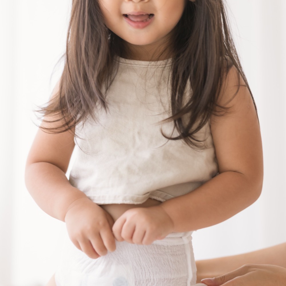 A smiling toddler standing in Little Rei bamboo pull-up pants
